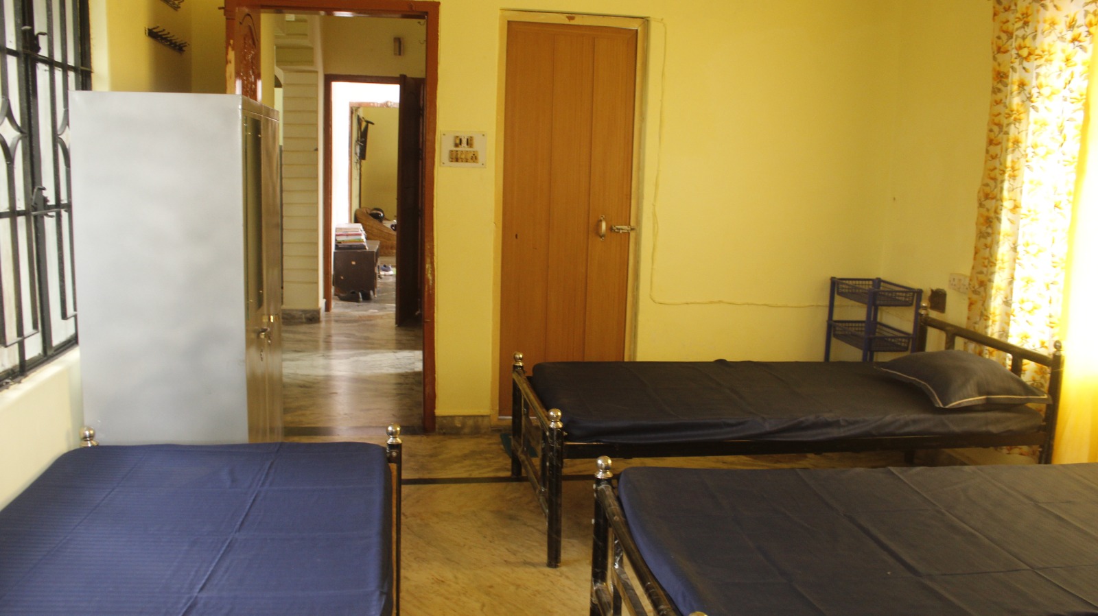 Room for rent at Sharma PG Home in Siliguri with beds and steel wardrobe