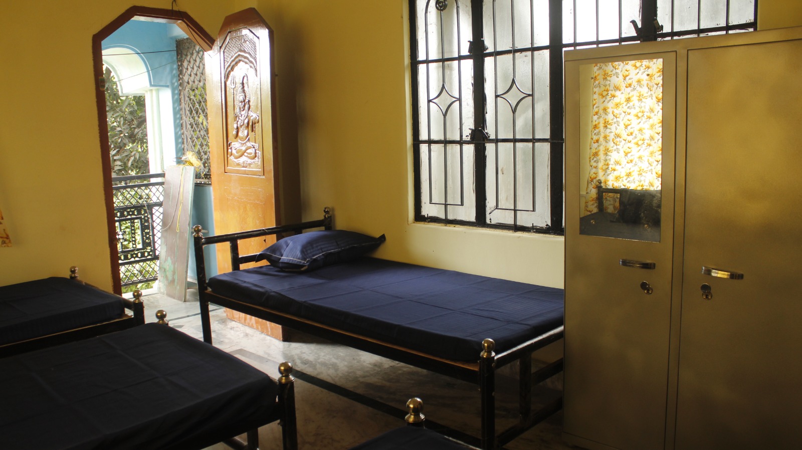 Room with two single beds, wardrobe and balcony door at Sharma PG Home, Siliguri